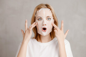 Surprised face of girl in white cloth mask for facial skin care