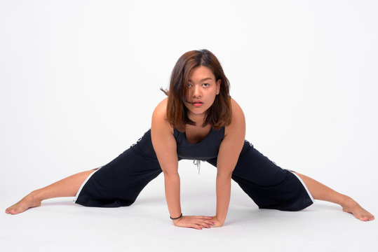 Full body shot of young beautiful Asian woman doing split