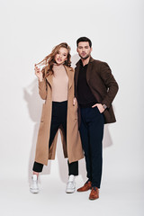 Looking perfect together. Attractive and well-dressed couple posing in studio. Isolated over grey...
