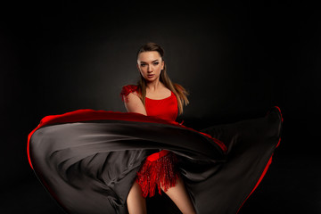 Young, beautiful girl dancing. The girl throws a red dress