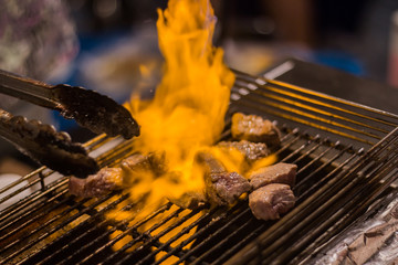 Grilling raw cube Australia beef on grate