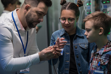 IT technician showing cable to children