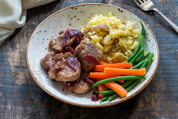 Pork in cranberry glaze with red onions, crushed potatoes and boiled vegetables - high angle view