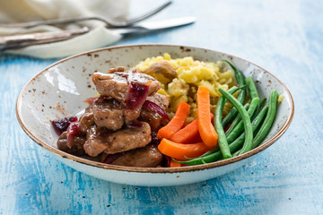Pork in cranberry glaze with red onions, crushed potatoes and boiled vegetables