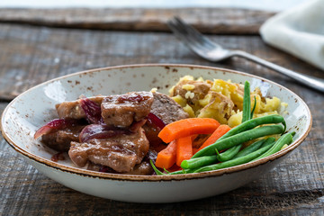 Pork in cranberry glaze with red onions, crushed potatoes and boiled vegetables