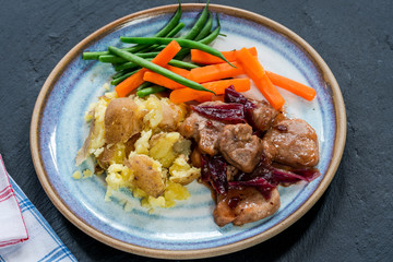 Pork in cranberry glaze with red onions, crushed potatoes and boiled vegetables - high angle view