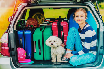Summer vacation, young girl in car trunk with dog in the car is ready for travel for family...