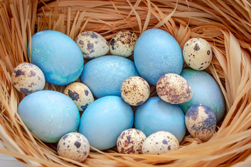 Easter eggs in the basket on a white wooden table. Top view.