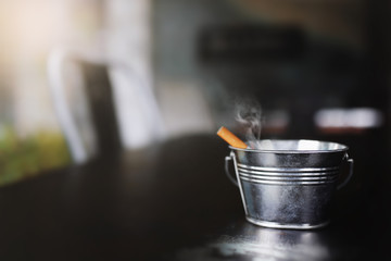 Small iron bucket,Metal ashtray with a cigarette ,very shallow depth of field and dark color toned.