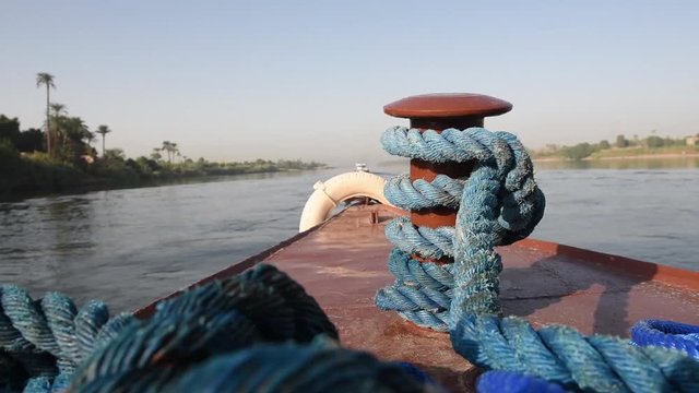 View across large wide river Nile in Egypt to riverbank through rural countryside landscape from luxury sailing cruise boat