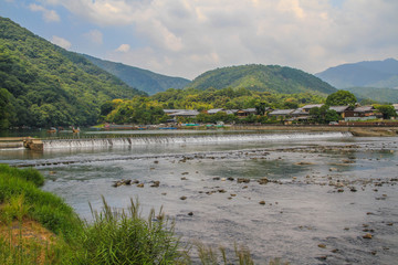 Landschaft und Berge am Damm über den Fluss Katsura im bei Touristen beliebten Ausflugsort Arashiyama bei Kyoto, Japan