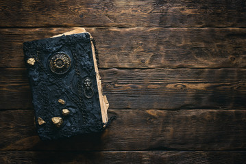 Ancient magic book on a wooden table background with copy space. Spellbook.