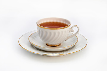 Tea in a white Cup on a saucer and a plate on a white background.