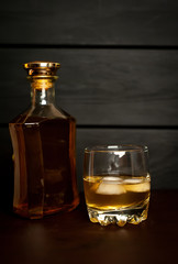 bottle of whiskey and a glass of whiskey on a wooden background