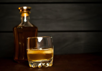 bottle of whiskey and a glass of whiskey on a wooden background