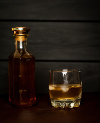 bottle of whiskey and a glass of whiskey on a wooden background