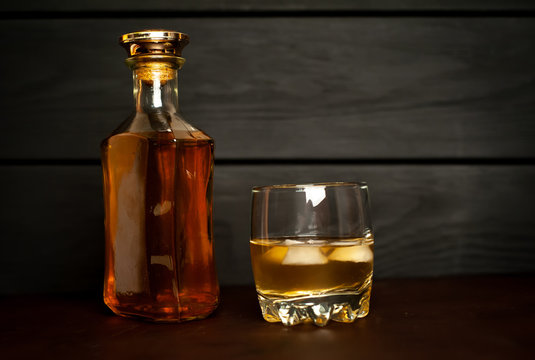 bottle of whiskey and a glass of whiskey on a wooden background