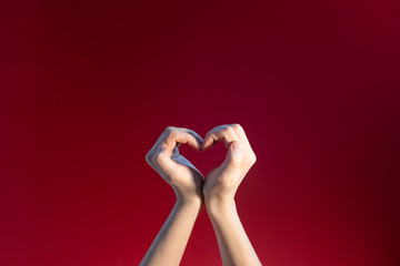 Heart made up of female hands on a red background