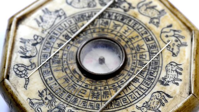 acupuncture needles on antique Chinese feng shui compass