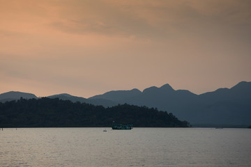 Boat at sea against mountains at sunset, tropical landscape of Thailand