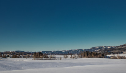 Obraz premium Snow-covered farmlands with mountains in Norway