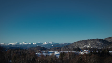 Winter landscape with snow covered mountains and farms in Norway
