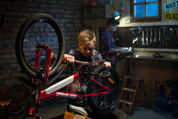 Obraz na płótnie Canvas Two boys repairing a bike in a garage