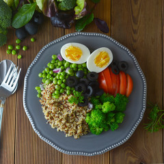 Layered vegetable salad with quinoa, green peas, broccoli, olives, red onion. Healthy food take away. LSquare image.