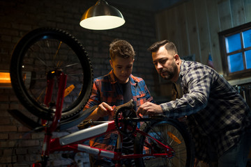 Fototapeta na wymiar Father and son repairing a bike in a garage