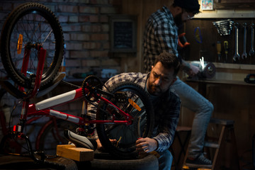 Obraz na płótnie Canvas Two men working in a bicycle repair shop