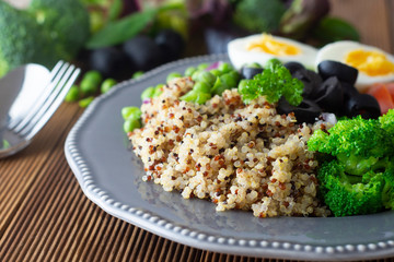 Quinoa salad with green pea,broccoli, olives. Healthy food, lunch over wooden background. Vegetarian food, snack.