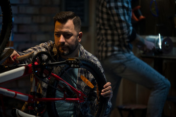 Obraz na płótnie Canvas Two men working in a bicycle repair shop