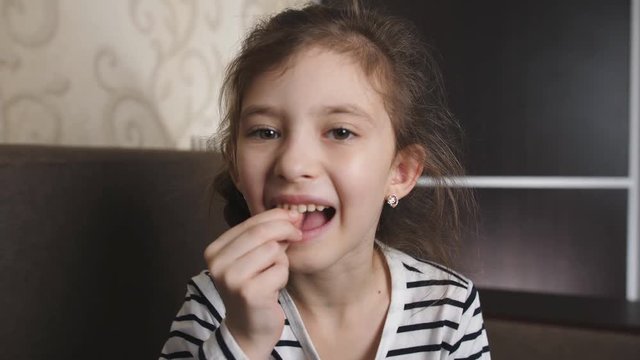 A cute young girls wobbles and shakes her loose tooth in an effort to remove it