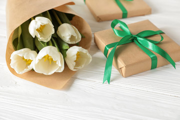 Fototapeta na wymiar White tulips bouquet and gift box, copy space on white wooden background, spring holidays gift concept.