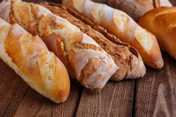 Assortment of baked bread on wooden table background