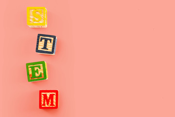 STEM education and Science Technology Engineering Mathematics concept theme with alphabet building blocks spelling out the acronym  STEM isolated on pink background with copy space