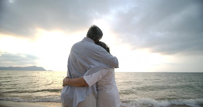 Asian senior couple embracing each other on the beach in slow motion.