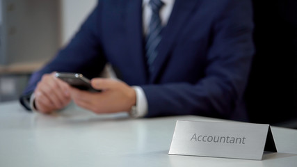 Male accountant reading news online on smartphone, scrolling pages on screen