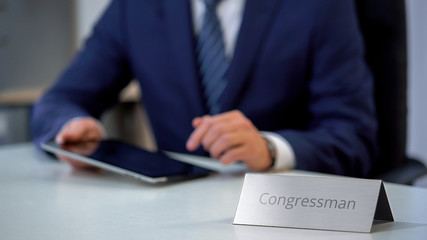 Busy congressman working on tablet pc, reading political news in online media