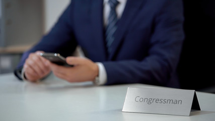 Congressman using smartphone for communication, examining political situation