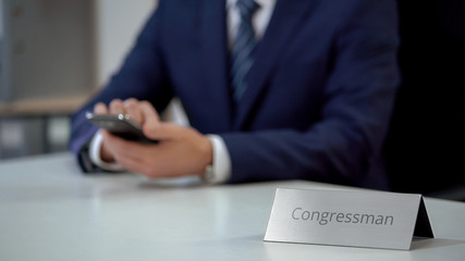 Congressman checking last political news on smartphone, examining situation