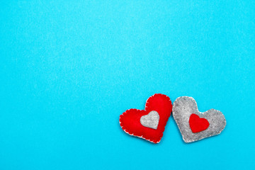 Two red felt handmade hearts on a blue background. Top view.