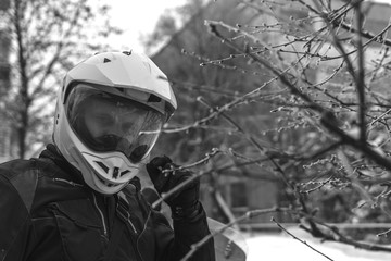 Fototapeta premium Rider man motorcyclist in helmet ortrait close up. Winter fun. snowy day. motorbike. active life style concept. winter clothes, equipment, defogger, back and white