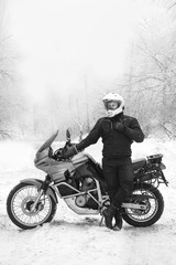 Rider man is sitting on adventure motorcycle. Winter fun. snowy day. motorbike and snow. black and white. off road dual sport travel tour, active life style concept. winter clothes, vertical photo