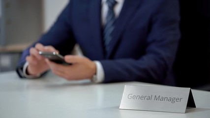 Company general manager typing message and viewing files on modern smartphone
