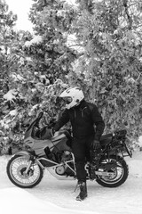 Fototapeta na wymiar Rider man is sitting on adventure motorcycle. Winter fun. snowy day. motorbike and snow. black and white. off road dual sport travel tour, active life style concept. winter clothes, vertical photo
