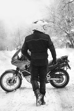 Rider man and adventure motorcycle. Winter fun. snowy day. the snow motorbike, back and white travel tour, active life style concept. winter clothes, equipment, vertical photo