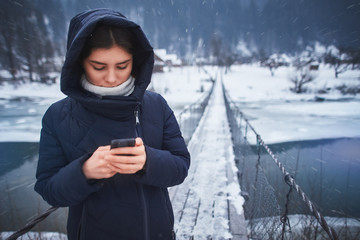 woman in winter standing on the bridge using phone