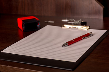 paper holder with a red pen lying on an office wooden table