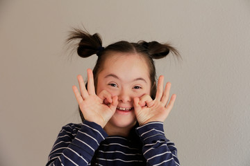 Cute smiling down syndrome girl on the grey background